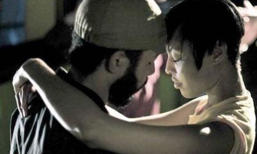 A man and a woman slow dance, their foreheads pressed together