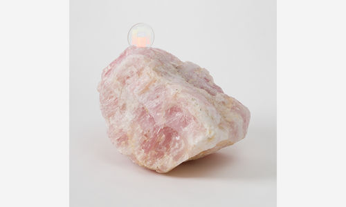 A large pink quartz with a disc-shaped memory crystal embedded in its top