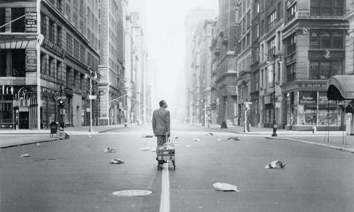 Harry Belafonte pulls a wagon behind him as he walks through a desolate city street