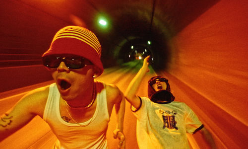 Two men in sunglasses run through a tunnel