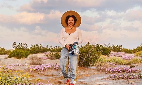 Krystle Hickman, wearing a sunhat and holding a camera in a desert landscape