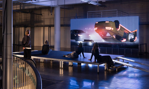Gallery view of visitors watching a video with an overturned car