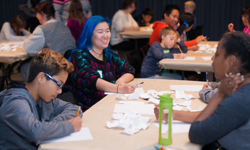 Smiling young teens sit at a table and write
