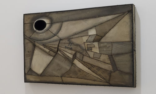 an abstract artwork hanging on a white wall