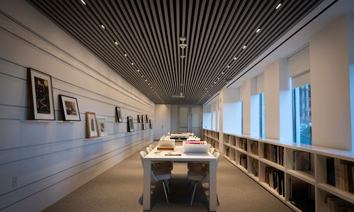 Empty room with tables and walls covered in works on paper