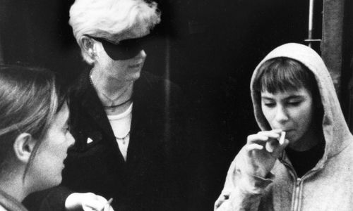 Three people smoke cigarettes and talk