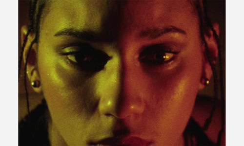 Close up of a woman's face, half bathed in yellow light