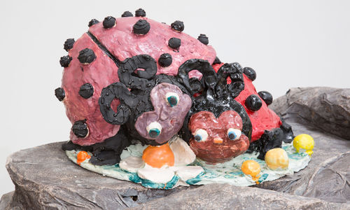Sculpture of two ladybugs with noses and large eyes laying on top of each other