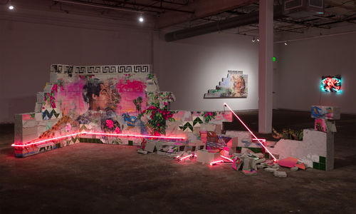 Installation featuring a crumbling wall of cinderblocks with handpainted images and pink neon lights