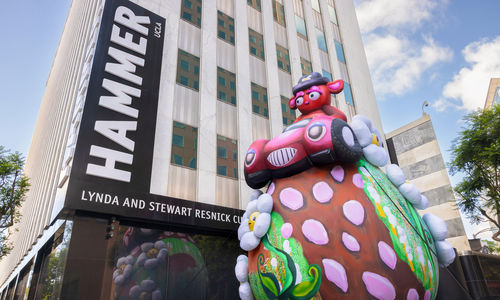 Massive outdoor inflatable portraying a stern-eyed bear in a hot-pink convertible atop a strawberry-studded shaped hilltop with daisies