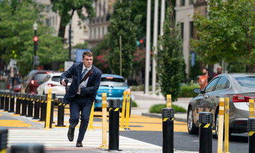 A man in a blue suit runs down a city street