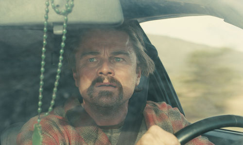 Leonardo DiCaprio drives, looking anxiously into the rear view mirror