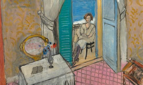 A seated woman seen through an open door, with the ocean visible beyond