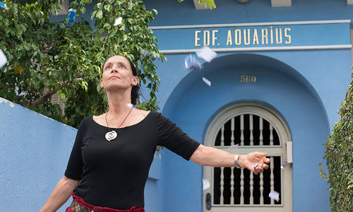 A woman stands in front of a building marked EDF AQUARIUS