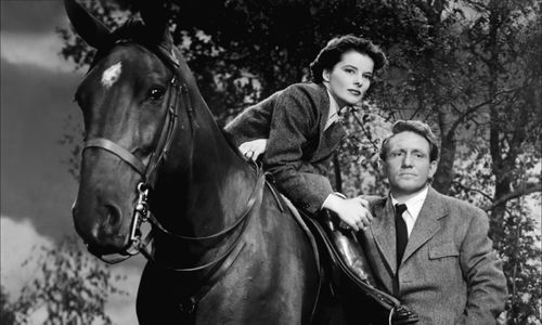 Katherine Hepburn, on a horse, next to Spencer Tracy