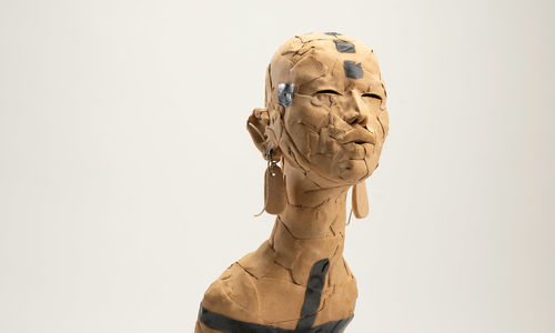 Ceramic figure with long earrings, body enveloped in beaded necklaces