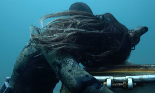 Underwater scene of a diver holding onto a sunken barrel