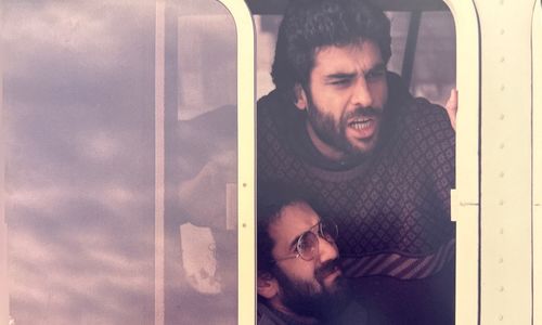 Two men lean out of an open train window