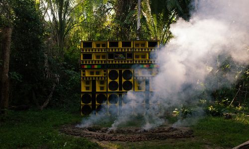 A wall of yellow speakers, surrounded by smoke