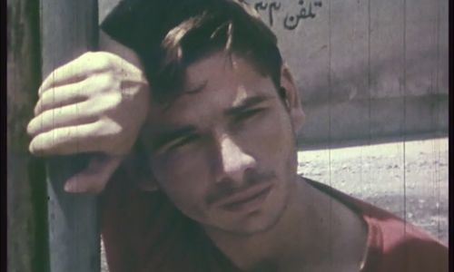 Close up of a young man leaning against a pole