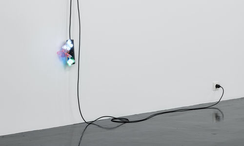 A black extension cord hangs from a wall, with three butterfly nightlights plugged into it