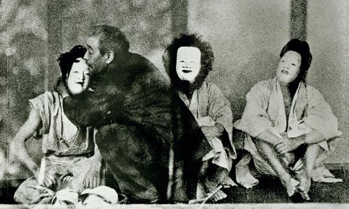 Three figures sit wearing white masks, while a man embraces the figure on the left