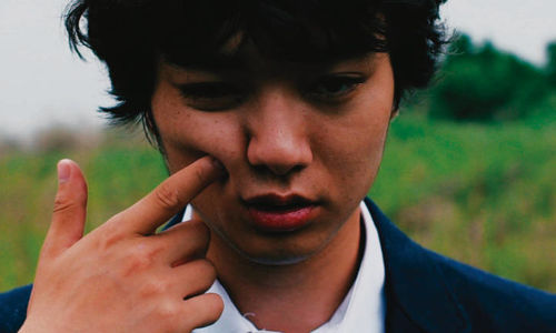 Close-up of a young man's face, with a finger pointing into their cheek