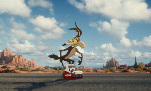 A cartoon coyote wearing ACME brand rollerblades stands on an empty desert highway