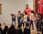 A group of students stand before another group sitting on the ground, posing.
