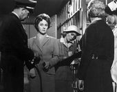 A woman stands in a prison, surrounded by four people