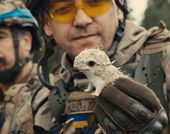 A man in military camouflage holds a small ceramic dragon figurine