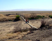 Two men work on a pipeline in a desert landscape