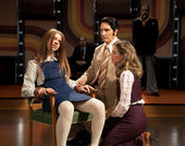 A man in a suit with another woman sits next to a girl on a chair