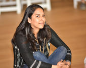 Russel Altamirano smiles at the camera, siting cross-legged and  on the hardwood floor at the Hammer Museum