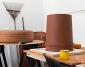 Photo of noé olivas's artist studio, showing sculptures of a tire and an upside down bucket on a worktable