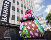 Massive outdoor inflatable portraying a stern-eyed bear in a hot-pink convertible atop a strawberry-studded shaped hilltop with daisies