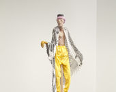 A sculpture of a man dressed in yellow pants stands on a black plinth